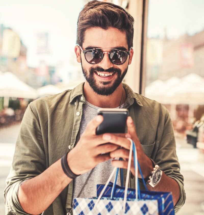 Person holding phone and shopping bags.